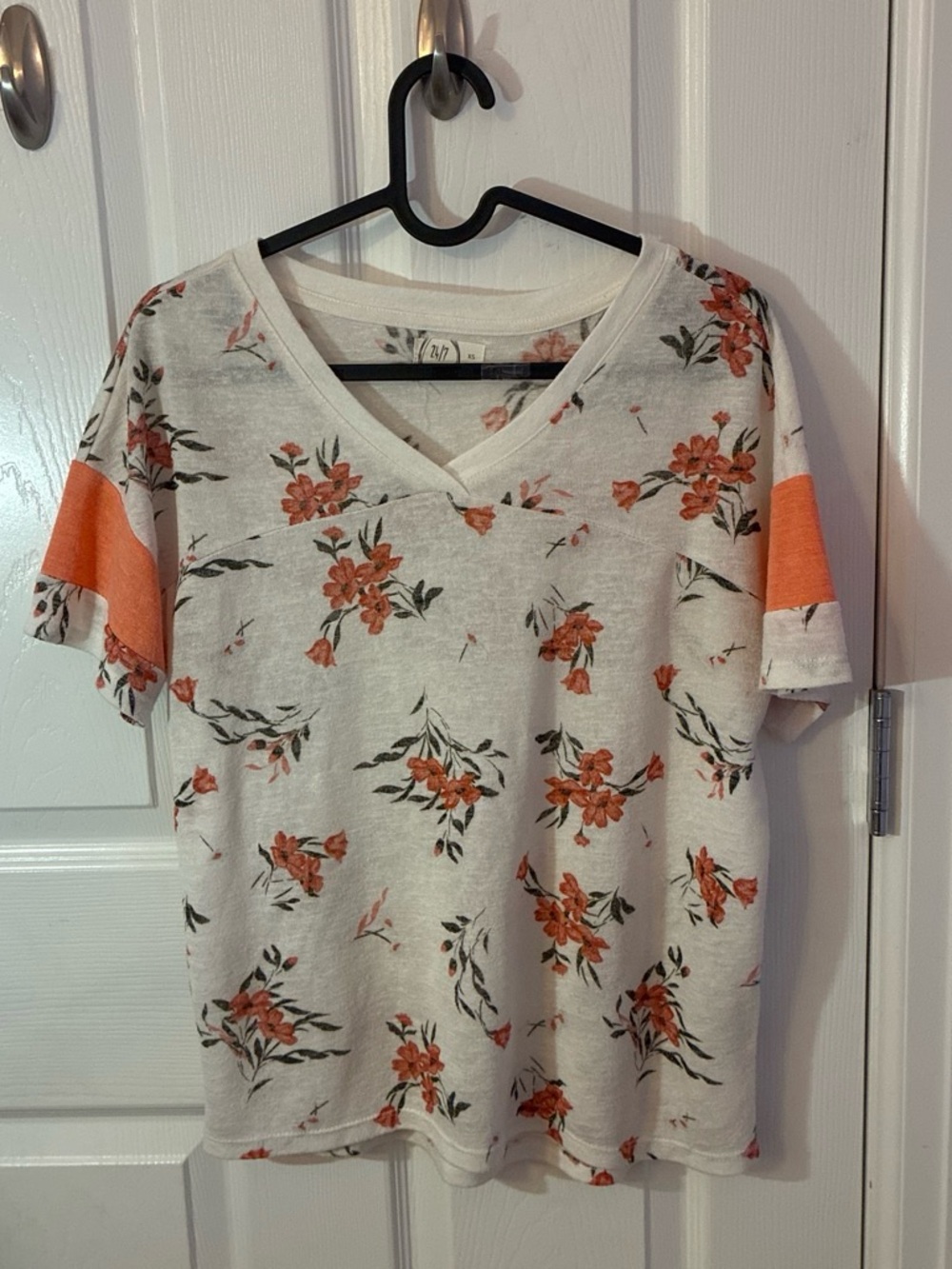 24/7. Coral/orange floral print on a white blouse